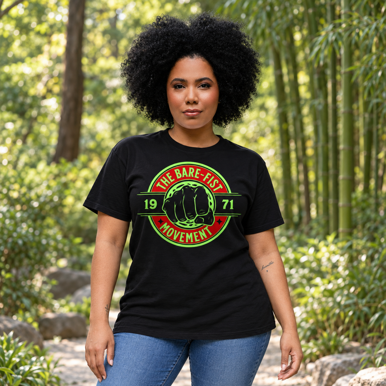 Woman wearing a black Bare-Fist Movement T-shirt in a sunlit woodland garden